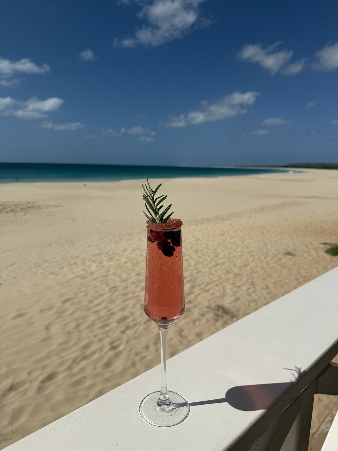 Cocktail pétillant aux fruits rouges et romarin, face à la plage