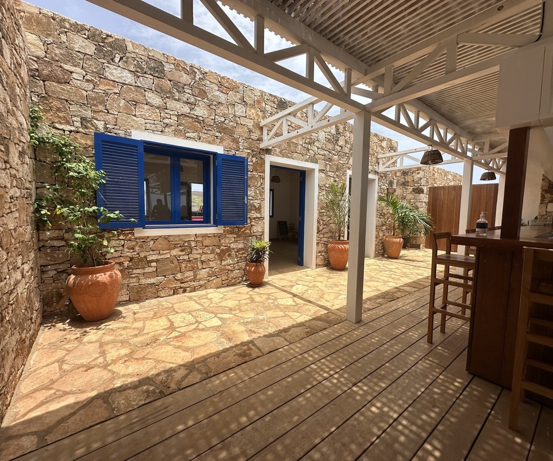 Le patio — volets bleus, pierre brute, charpente blanche
